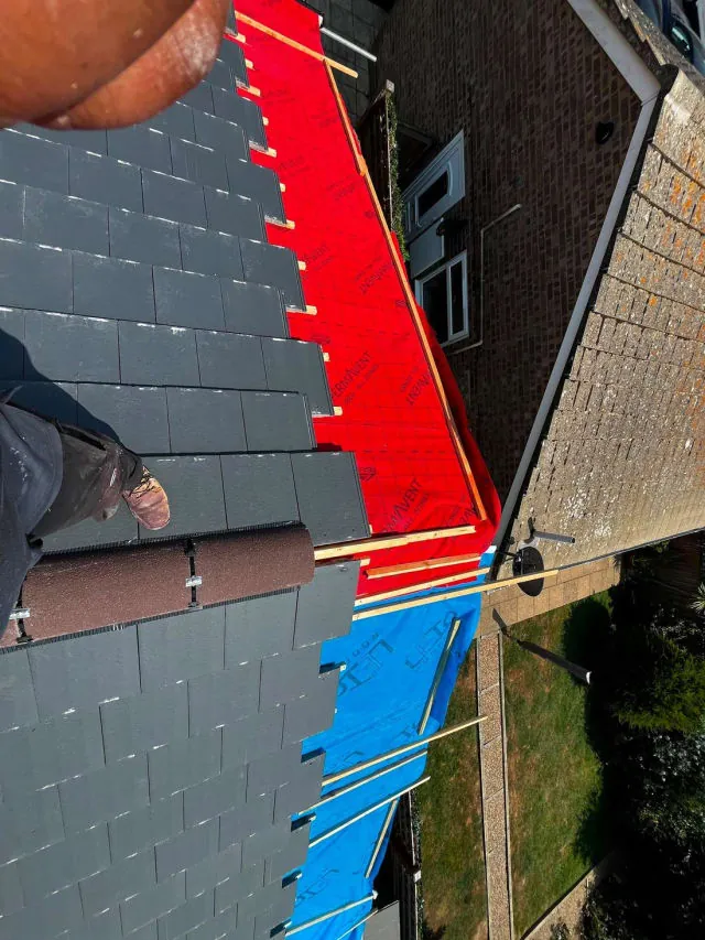 New slates being laid over breathable membrane on a re-roof in Sussex