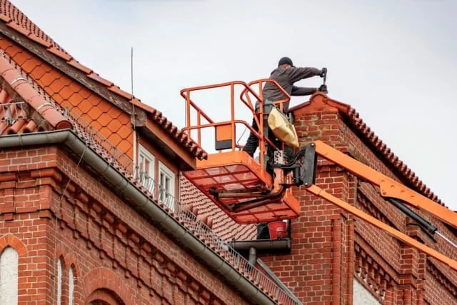 Roofer repairing slipped tiles on a pitched roof in Brighton